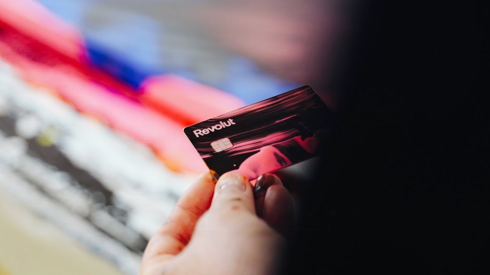 A Revolut card from The Art of Payments collection held in front of a painting by Alex Kuznetsov, still from the Revolut film